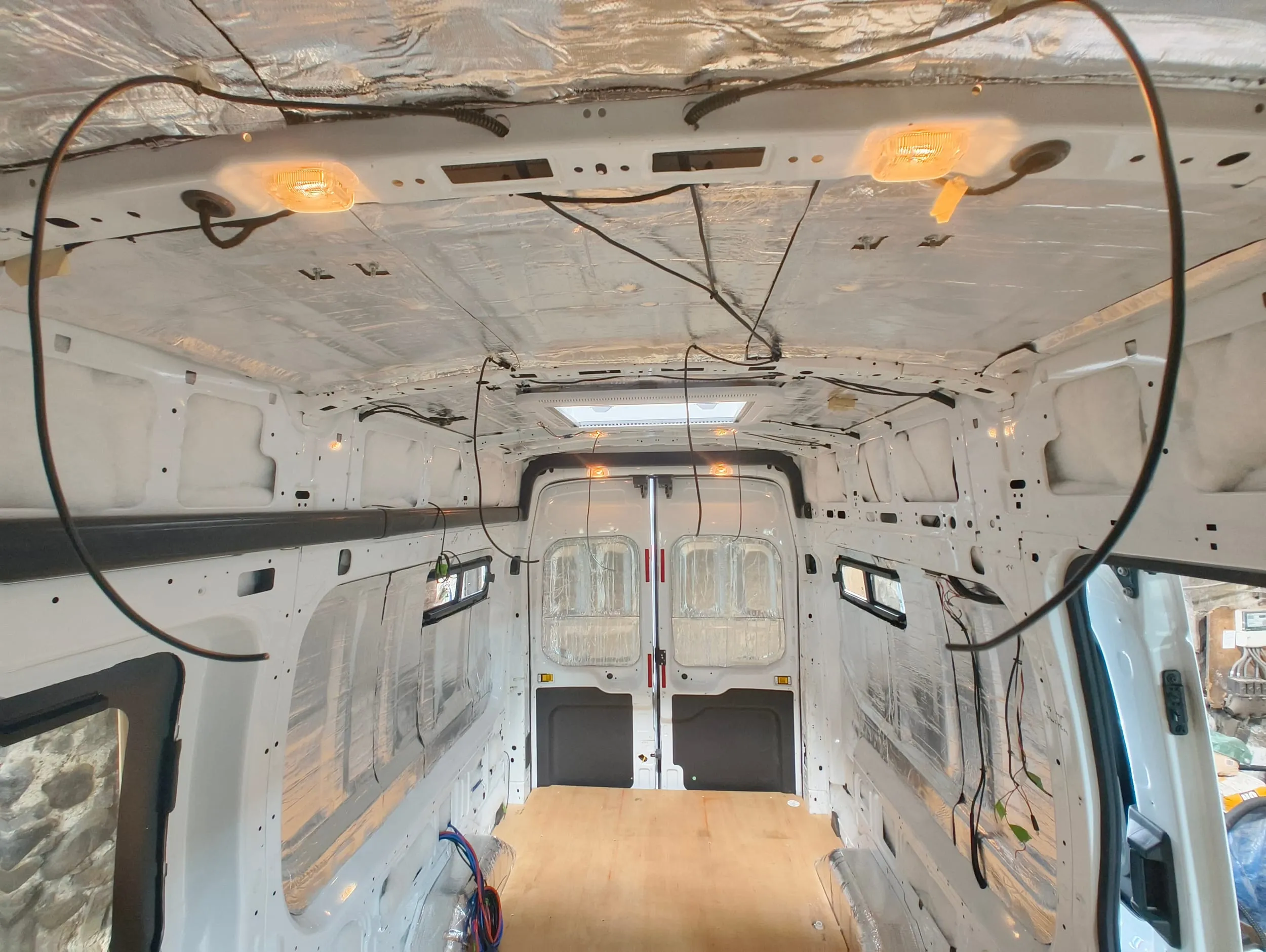 Cable runs taped across the bare metal roof of the van before any lining goes on.